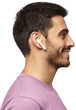 © Damir Khabirov - Side portrait of smiling young man listening to music or radio, uses modern wireless earphones