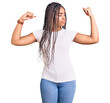 © Krakenimages.com - Young african american woman with braids wearing casual clothes showing arms muscles smiling proud. fitness concept.