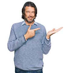 Wall Mural - Middle age handsome man wearing casual clothes amazed and smiling to the camera while presenting with hand and pointing with finger.