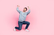 Full body photo of nice young guy raise hands carry invisible weight empty space dressed trendy blue look isolated on pink color background