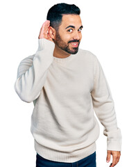 Sticker - Young hispanic man with beard wearing casual white sweater smiling with hand over ear listening an hearing to rumor or gossip. deafness concept.