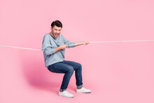 Full Length Photo Of Excited Guy Competitor Pulling Tug War String Isolated On Pastel Color Background