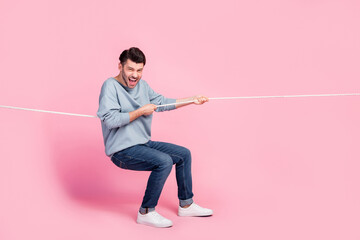 Wall Mural - Full length photo of excited guy competitor pulling tug war string isolated on pastel color background