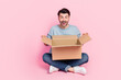 Full length photo of attractive young guy open unpack box receive online order dressed trendy blue look isolated on pink color background