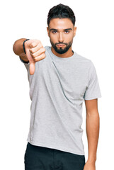 Sticker - Young man with beard wearing casual grey tshirt looking unhappy and angry showing rejection and negative with thumbs down gesture. bad expression.