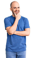 Canvas Print - Young handsome man wearing casual t shirt looking confident at the camera smiling with crossed arms and hand raised on chin. thinking positive.