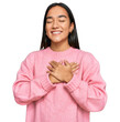 Young asian woman wearing casual winter sweater smiling with hands on chest with closed eyes and grateful gesture on face. health concept.
