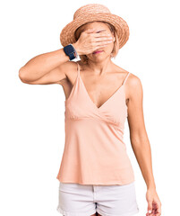 Sticker - Young blonde woman wearing summer hat covering eyes with hand, looking serious and sad. sightless, hiding and rejection concept