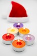 Vertical shot of colorful burning candles with a Christmas Santa Claus Hat in the background