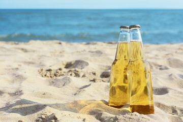 Poster - Bottles of cold beer on sandy beach near sea, space for text