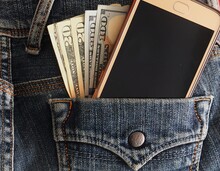 Cash Money In US Dollar Currency And Smartphone In The Denim Blue Jeans Back Pocket, Concept Of Money Making /Online Business/Side Hustle/ Young Business Owner