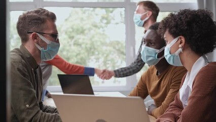 Wall Mural - business people in protective masks working in a modern coworking center.