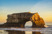 Natural Stone Rock Archway In Pacific Ocean At Sunset, Natural Bridges State Park.