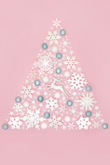 Wall Mural - Festive Christmas tree shape abstract north pole concept with snowflake, reindeer, star and ball decorations on pink background. Fun magical design for the holiday season.