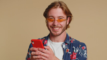 Handsome tourist young man using smartphone typing new post on web, browsing, searching, addiction of social networks, show thumbs up like, positive feedback, recommends wifi cellular connection 5G