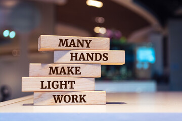 Wooden blocks with words 'Many hands make light work'.