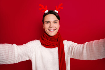 Canvas Print - Selfie photo of positive guy wear deer horns toothy beaming smiliing take portrait cadre enjoy winter time spirit isolated on red color background