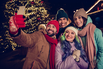 Sticker - Photo of four cheerful positive fellows hold telephone make self portrait evening evergreen lights city center outdoors