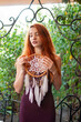© pliekhova - Portrait of lovely slim redhead girl in wine dress and dreamcatcher craft talisman