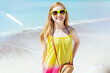 Portrait of happy girl in sunglasses at beach in colorful dress