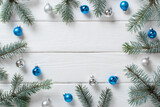 Fototapeta Panele - Fir branches with Christmas silver and blue glass balls on a white wooden background. Christmas minimalism. Space for copying. Flat position, top view.