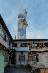 Wall Mural - Old shabby house in the slum district on background of moredn skyscraper