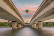 Unidentified hot air balloon passing over the commonwealth bridge, Canberra. with capital hill in the background during sunrise.