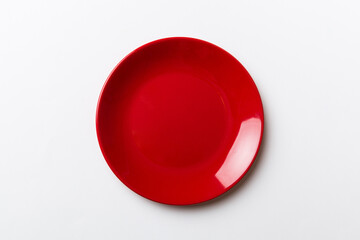 Top view of isolated of colored background empty round red plate for food. Empty dish with space for your design