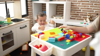 Poster - Adorable girl and boy playing with construction block pieces sitting on table at kindergarten