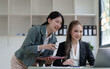 © NanSan - Female business worker with colleagues in Thailand working together at office desk, Female office worker business suit working with document file and paper work.