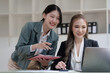 © NanSan - Female business worker with colleagues in Thailand working together at office desk, Female office worker business suit working with document file and paper work.