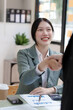 © NanSan - Female business worker with colleagues in Thailand working together at office desk, getting shaking hands, successful and agreement concept