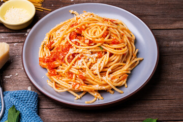 Canvas Print - Delicious spaghetti cheese pasta served on a plate Vegetables, Italian tomato sauce and spices arranged on a wooden table, top view