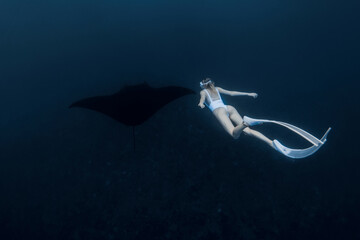 Wall Mural - Woman freediver with long white fins swim with manta ray. Freediving with big manta ray