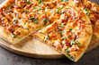 American California pizza with chicken, barbecue sauce, cheese and onions close-up on a wooden board on the table. Horizontal