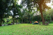 nature camping tent with flysheet on green grass meadow or lawn and family relax camp in tree forest or autumn natural garden on morning for holiday at lan sang national park campground in thailand