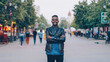 © silverkblack - Portrait of emotional African American man hipster standing in street with arms crossed and looking at camera when men and women are whizzing by.