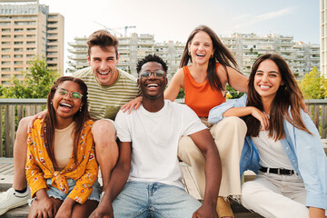 Wall Mural - Happy multiracial young people smiling together looking at camera, five teenage friends having fun and laughing taking picture outside on city street. Lifestyle Concept. High quality photo