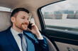 © VK Studio - Happy business owner sitting on back seat in car and talking on phone