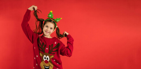 Sticker - cute little girl with a cute facial expression posing in a Christmas sweater on a bright red background emotional, funny