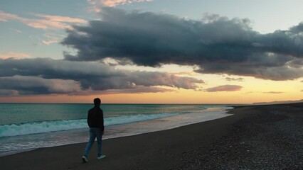 Wall Mural - Boy walking alone on the shore after sunset beautiful sky