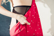 young woman zipping red dress with white dotts on trasperent black stocking belt 