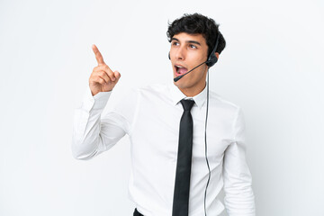 Telemarketer man working with a headset isolated on white background pointing away