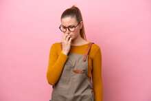 Woman With Apron Isolated On Pink Background Having Doubts