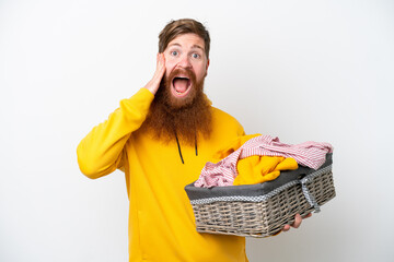 Wall Mural - Redhead man with beard holding a clothes basket isolated on white background with surprise and shocked facial expression