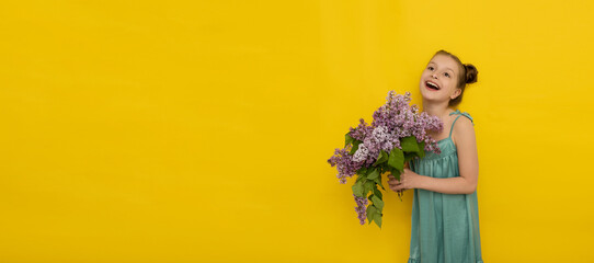 happy smiling little girl in summer dress holding lilac bouquet on yellow background, spring mood