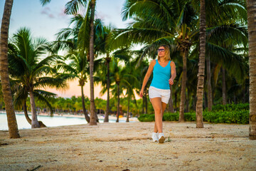 Wall Mural - Woman walking on sunny, tropical beach at daybreak
