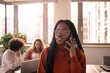 © jessica - Black girl in foreground is taking a break in the office, using phone