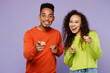 © ViDi Studio - Young fun couple two friends family man woman of African American ethnicity wear casual clothes together look camera laugh watch comedy movie point finger on you isolated on plain purple background.