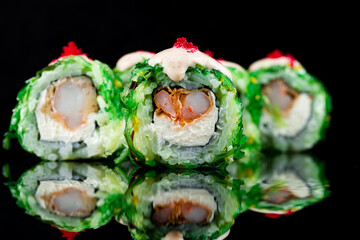 Wall Mural - Sushi rolls with shrimp tempura, cream cheese, seaweed, topped with sauce and red flying fish caviar.